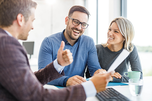 Young happy couple and their insurance agent talking about plans on a meeting in the office.