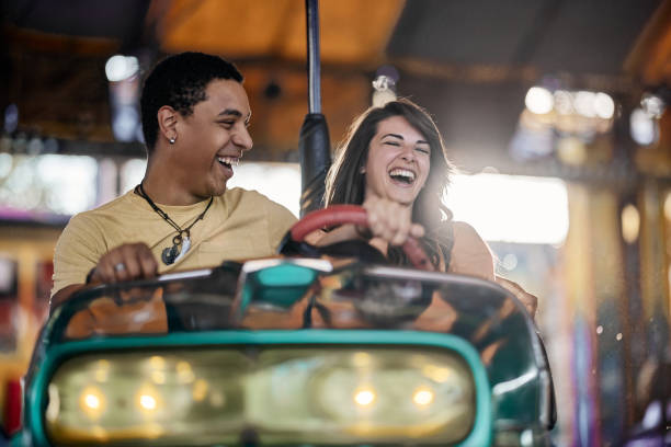 istock Cheerful couple having fun in bumper car at amusement park. 1921539095