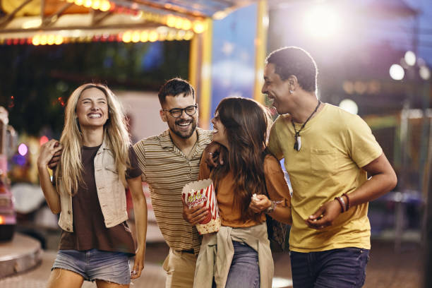 istock Happy friends having fun while eating popcorn at amusement park. 1921548580