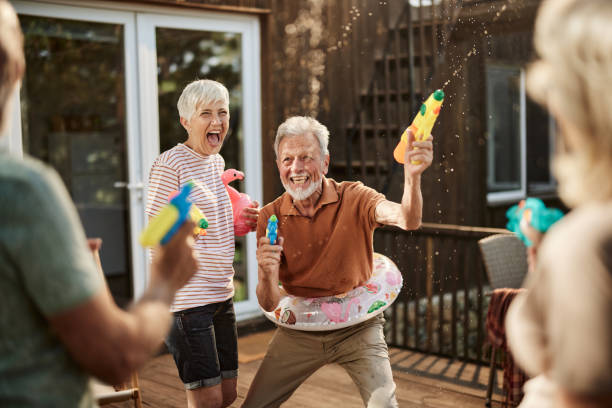 istock Cheerful senior couples having fun during water gun fight on a terrace. 1921559116