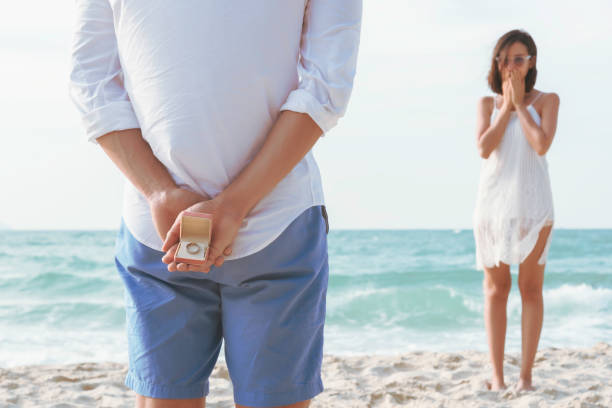 istock Young man holding white ring making marriage proposal in the beach.Valentine, Summer and Travel Concept. 1921560192