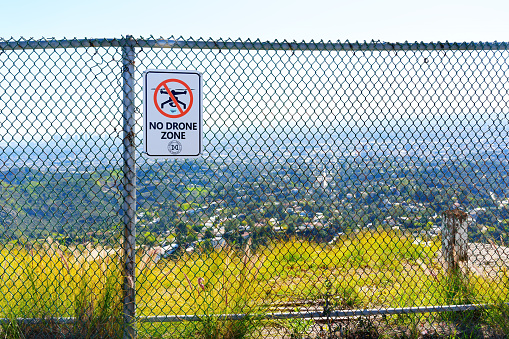 Los Angeles, California - February 1, 2023: Warning Sign Indicating a 'No Drone Zone' Area Mounted on a Chain-Link Fence Overlooking the City