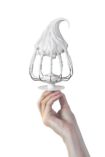 Woman's hand hold Whisk with cream, whisk with meringue cream isolated on white photo