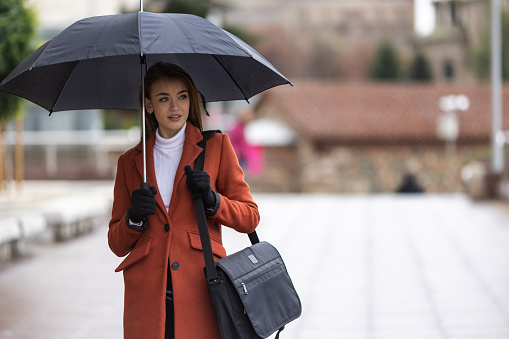 Brunette with umbrella walking in the city