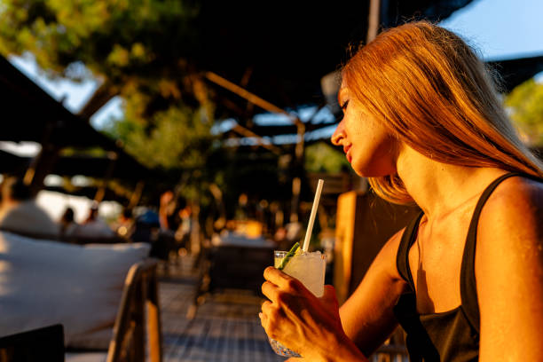 In the verdant setting of the cafe garden, the young woman's drink mirrors the freshness around her