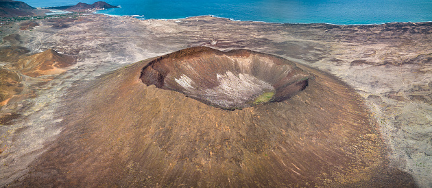 Aerial view of the Viana Volcano on São Vicente, Cape Verde, showcasing the distinct crater with layered earthen textures against a coastal backdrop