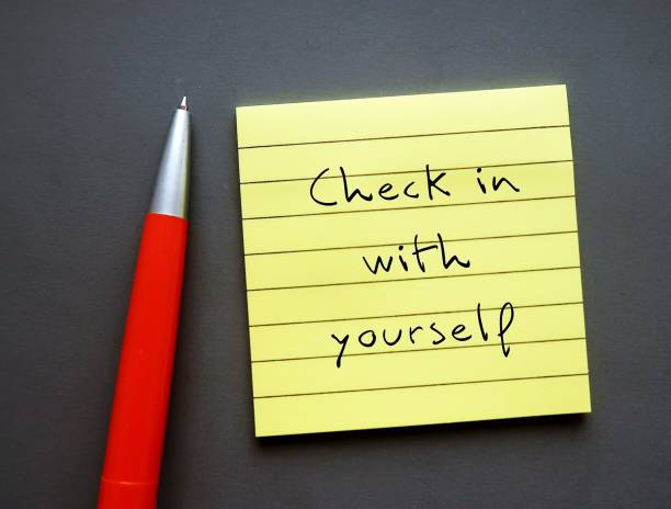 Note paper on gray background with handwritten text - Check in with yourself - carving out time each day to ask yourself how youre doing