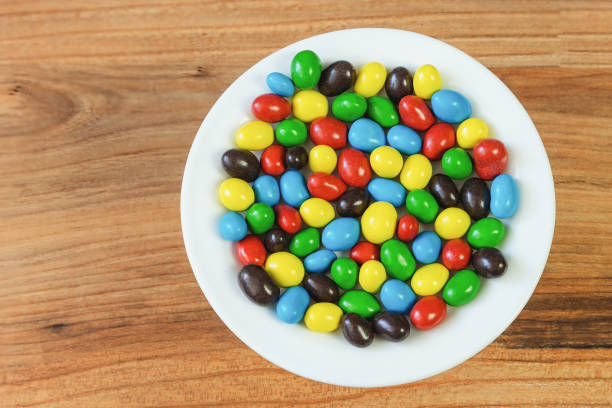 Peanuts in milk chocolate and sugar peel on a plate on a pine table