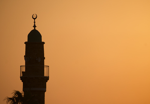 Captivating silhouette of the Al-Bahr Mosque Minaret against a warm sunset sky in Tel-Aviv, Israel.
