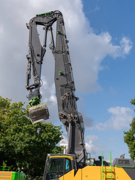 istock Excavator boom against a background of blue sky with white clouds. 1921663120