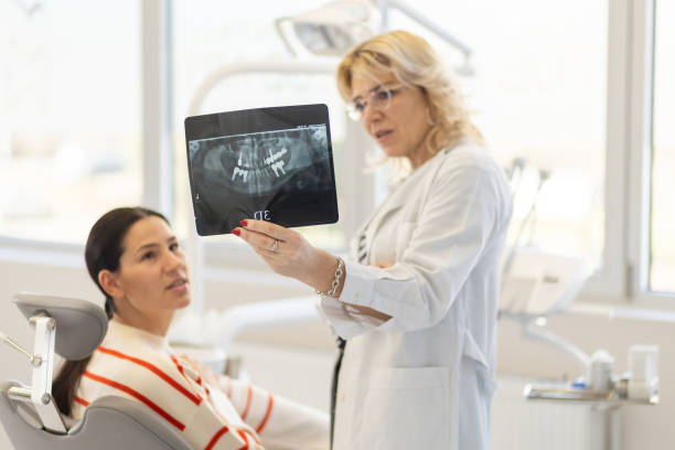 istock Mature female dentist explaining teeth X-Rays to patient at dental office 1921665287