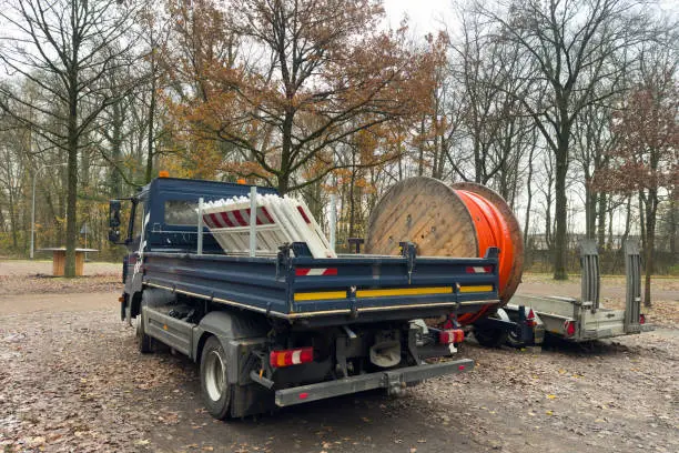 Photo of Small truck with plastic mobile barriers. Wooden reel with orange cable