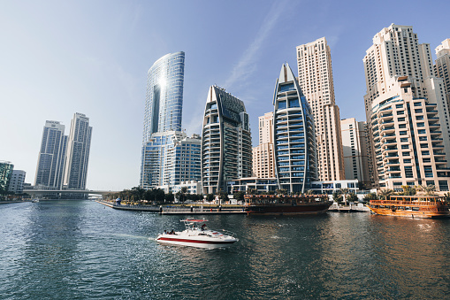 View over Dubai Marina towards with building construction and boats during a sunny day. Dubai, UAE. November 27, 2022