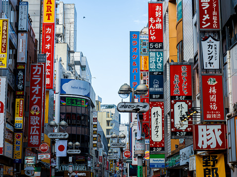 Neon lights and illuminated billboards of Shinjuku glittering at night above crowds of shoppers in the heart of Tokyo, Japan’s vibrant capital city.