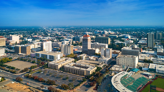 Aerial skyline view of Downtown Fresno during Autumn centered on the Pacific Southwest Building, with a hazy sky and skyline in the distance.