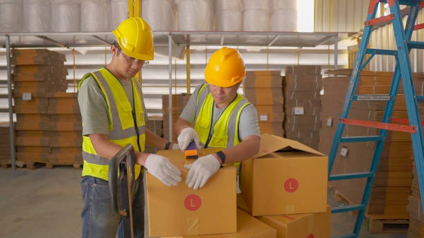 istock A workers with yellow hard hat packing cardboard box with scotch tape. 1921695110