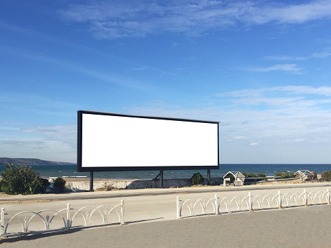 Empty wide frame billboard at the coastline with sea and sky background. Billboard frame with clipping path
