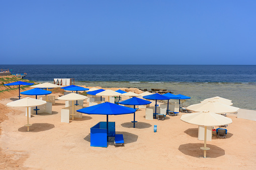 Sun loungers with umbrellas on the beach in Marsa Alam at sunrise, Egypt