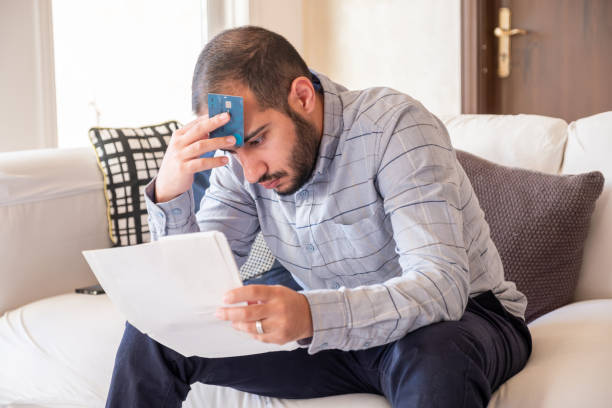 istock male holding bank card while feeling stressed due to financial issue 1921719441
