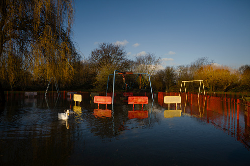A flooded and multicoloured children's playground sits in floods on a sunny day.