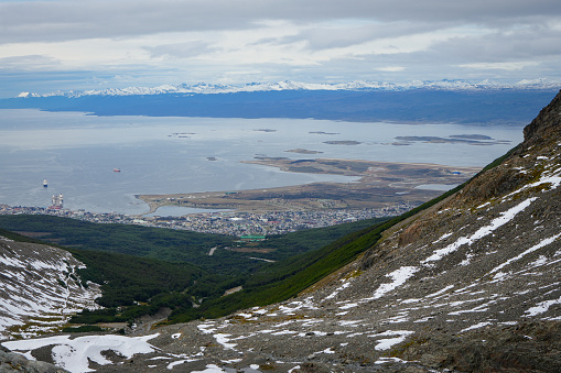 The city of Ushuaia is the world's southernmost city, and can be seen here against the backdrop of the Beagle Channel. The foreground of the photo is dominated by the slopes that lead up to the Martial Glacier, with an evergreen forest just below.\n\nChile can be seen in the far distance.