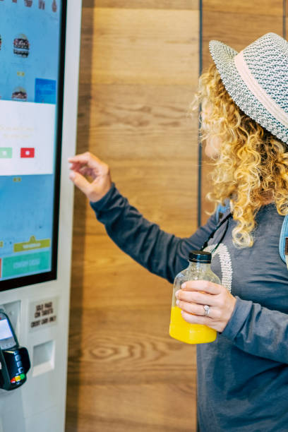 istock Woman make food order in modern display at fast food restaurant - self-service panel technology and people in travel lifestyle taking hamburger to eat 1921773875