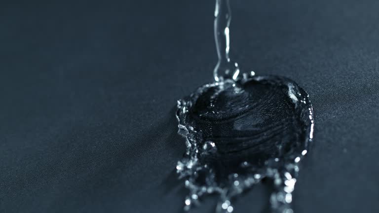 Super slow motion of falling water drops on waterproof cloth texture in detail.