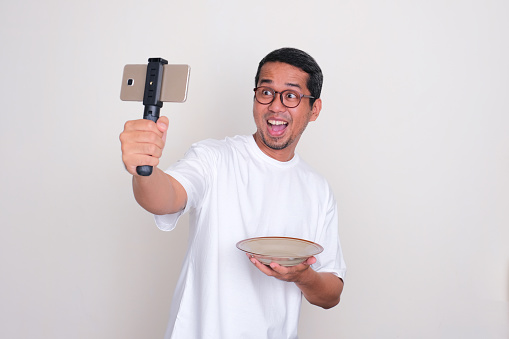 A food vlogger looks excited when showing empty dinning plate during making the content