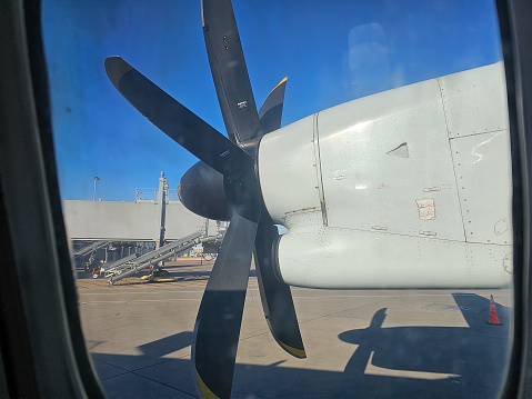 A look through a window at a stationary propeller of a plane.