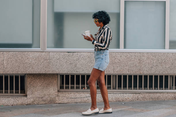 istock woman walking with mobile phone and cup 1921865485