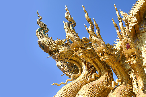 Traditional thai dragon statue against blue sky at a temple in Thailand