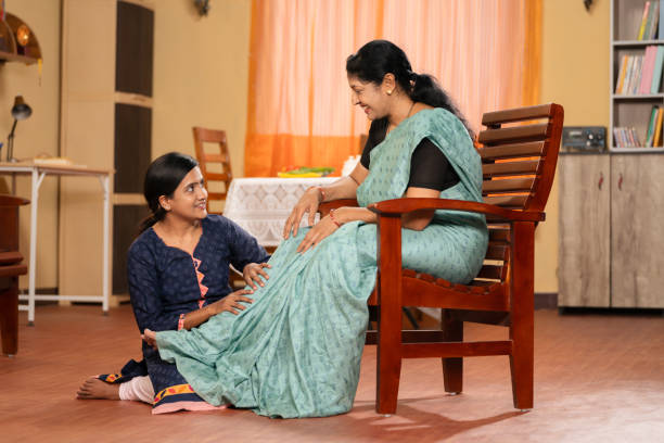 Close-up shot of two female roommates talking in living room, while sitting in a sofa and drinking hot coffee in the morning