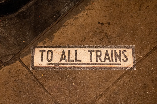 A sidewalk sign saying: To All Trains. New York, USA