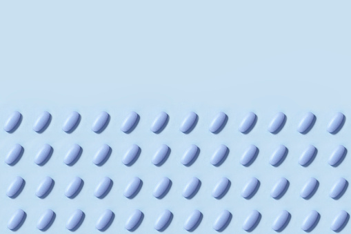 Blue pills in a row on blue background
