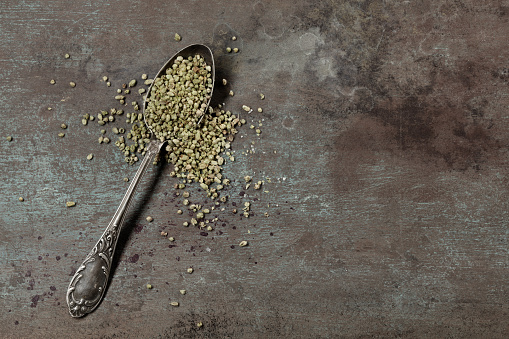 Organic Heap of dried thyme seeds in an old metal spoon on a grunge background. Spices on a dark rusty background.