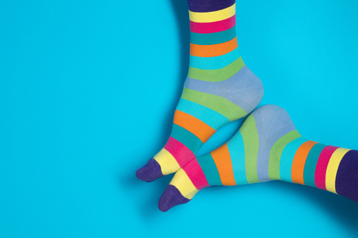 Male feet in rainbow-colored socks on а blue background.  Copy space