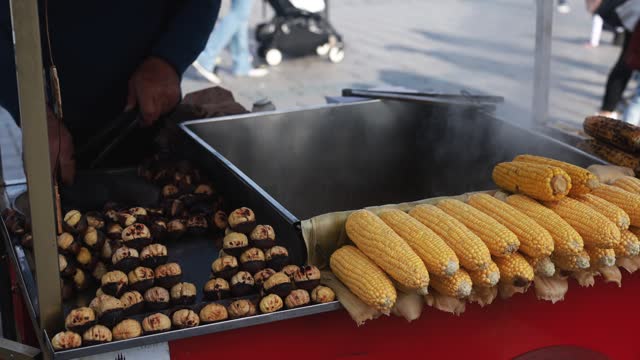 Turkish man with street food cart sells chestnuts and corn cobs - Travel concept