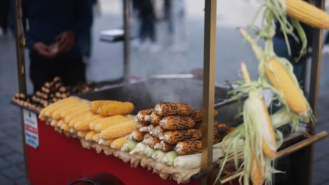 Turkish street food seller with cart sells chestnuts and corn cobs