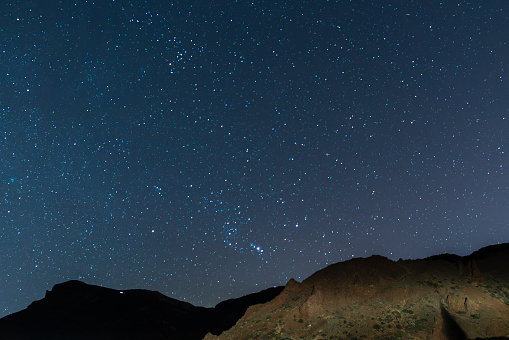 Beautiful astrophotography of the skies of Tenerife shot from the Teide National Park, where mountains and bright stars are seen in the sky, in Tenerife, Canary Islands, Spain, Europe