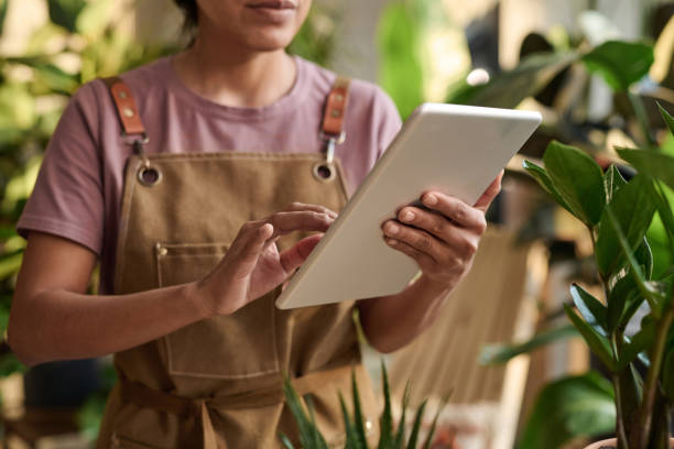 istock Houseplants Seller Scrolling Through Information on Tablet 1921982569
