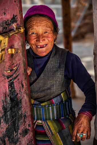 Portrait of happy Tibetan woman in small village in Upper Mustang. Mustang region is the former Kingdom of Lo and now part of Nepal,  in the north-central part of that country, bordering the People's Republic of China on the Tibetan plateau between the Nepalese provinces of Dolpo and Manang.