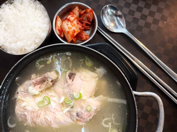 Overhead view of Samgyetang - Korean Ginseng Chicken Soup served with rice and kimchi. A popular summer stamina food in Korea.