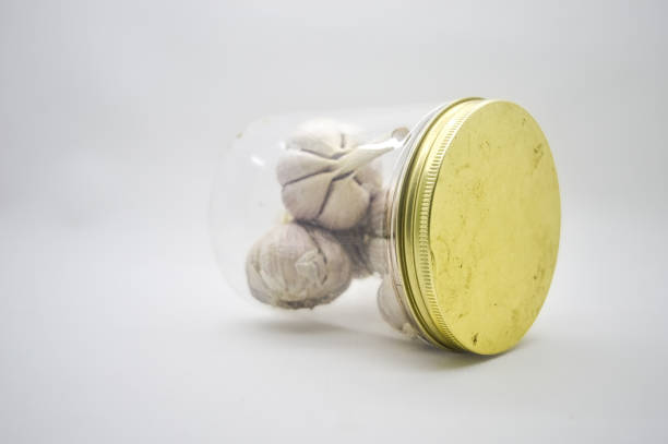 istock bunch of garlic in a tilted plastic jar isolated on white background 1921995104