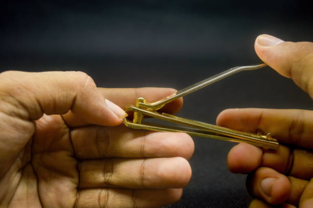 istock hand cutting nails using a gold nail clipper isolated on black background 1921996134