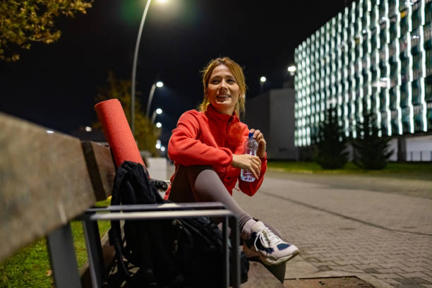istock Young woman sitting on a bench and drinking water after hard training 1922000358