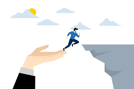 Confident businessman jumping from helping giant hand to reach cliff target. Support in business for success, guidance and motivation to overcome business obstacles, career growth concept.