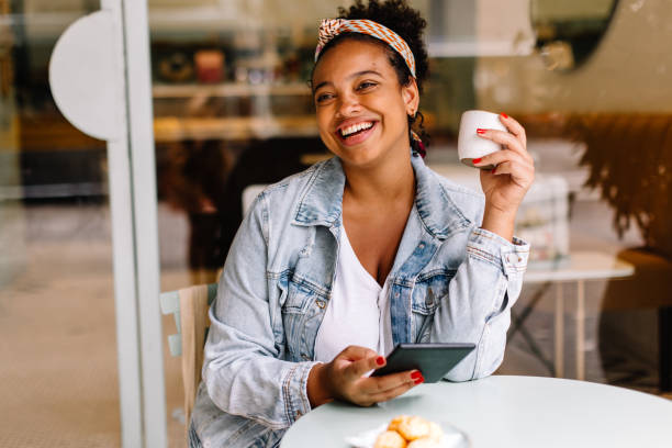 istock Happy young woman enjoying a cup of coffee at a cafe while using a digital tablet 1922007805