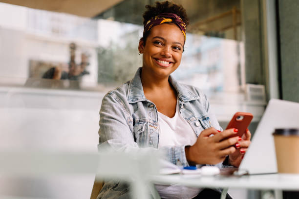 istock Young woman enjoying coffee break at a cafe, using phone 1922008843