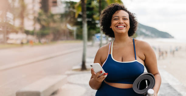 istock Fitness at the beach: Woman smiling and going for a workout with her phone in hand 1922013086