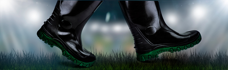 Dark rubber boots walk on meadow